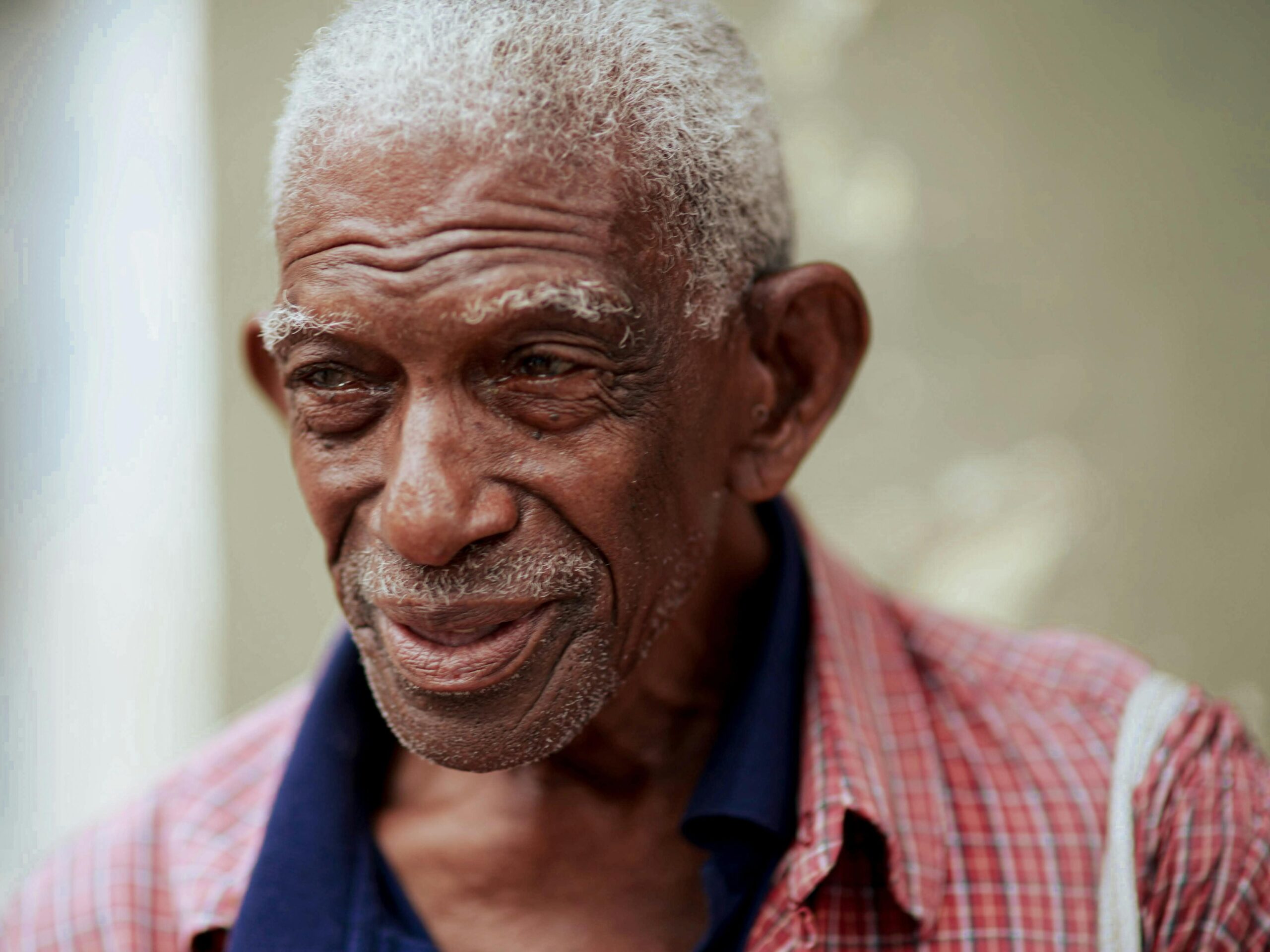 A close-up portrait of a smiling elderly man with white hair and wisdom in his eyes.